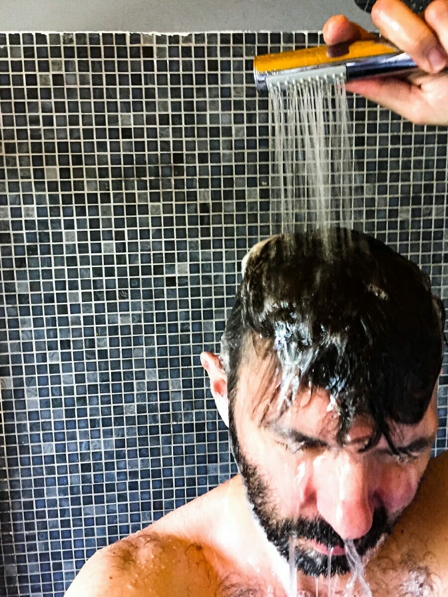 Man taking a shower using hand shower