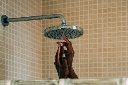 Female hands visible in shower enclosure directly beneath shower flow